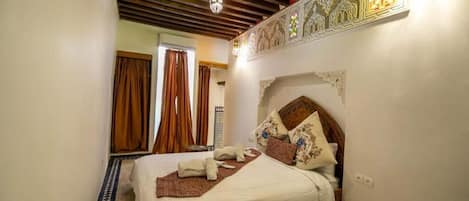 A bedroom with a bed, a telephone, and a decorative wall.