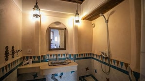 A bathroom with a sink, mirror, shower, and decorative tiles. - Dar Rass Jnane (Fes)