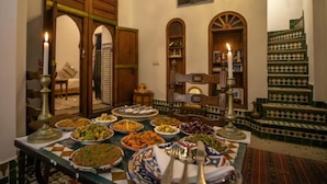 A dining area with a table set for a meal, surrounded by traditional decor and a view of a staircase. - Dar Rass Jnane (FES)