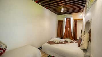 A bedroom with two beds, a wooden ceiling, and a patterned rug.