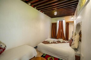 A bedroom with two beds, a wooden ceiling, and a patterned rug. - Dar Rass Jnane (Fes)