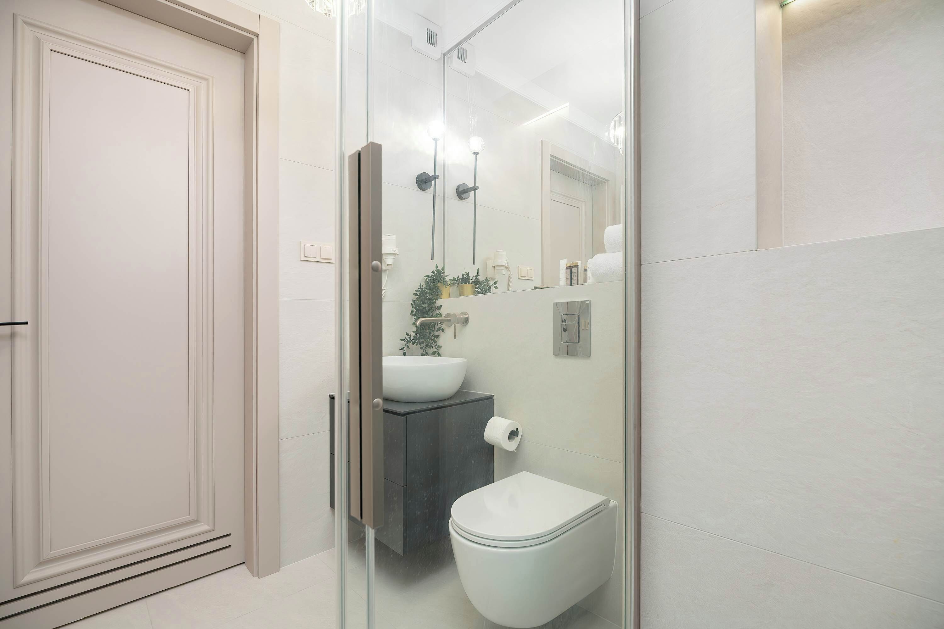 Ein modernes Badezimmer mit Duschkabine aus Glas, einer weißen Toilette und einem Waschtisch.