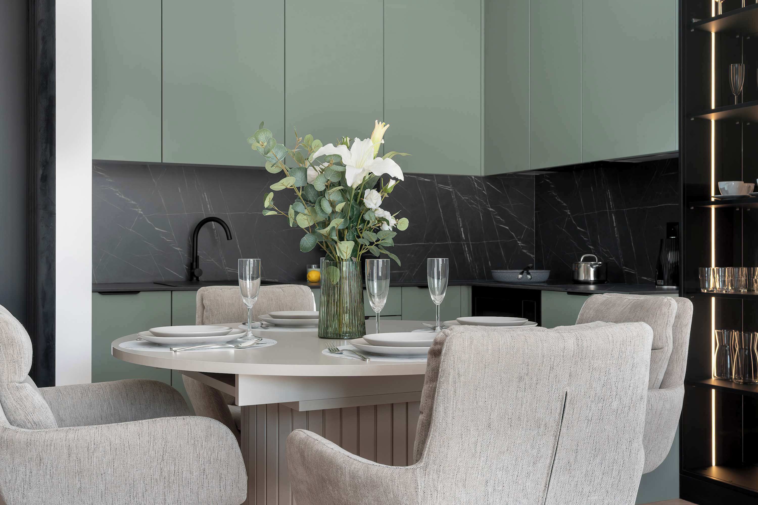 A dining area with a round table set for four, surrounded by upholstered chairs.