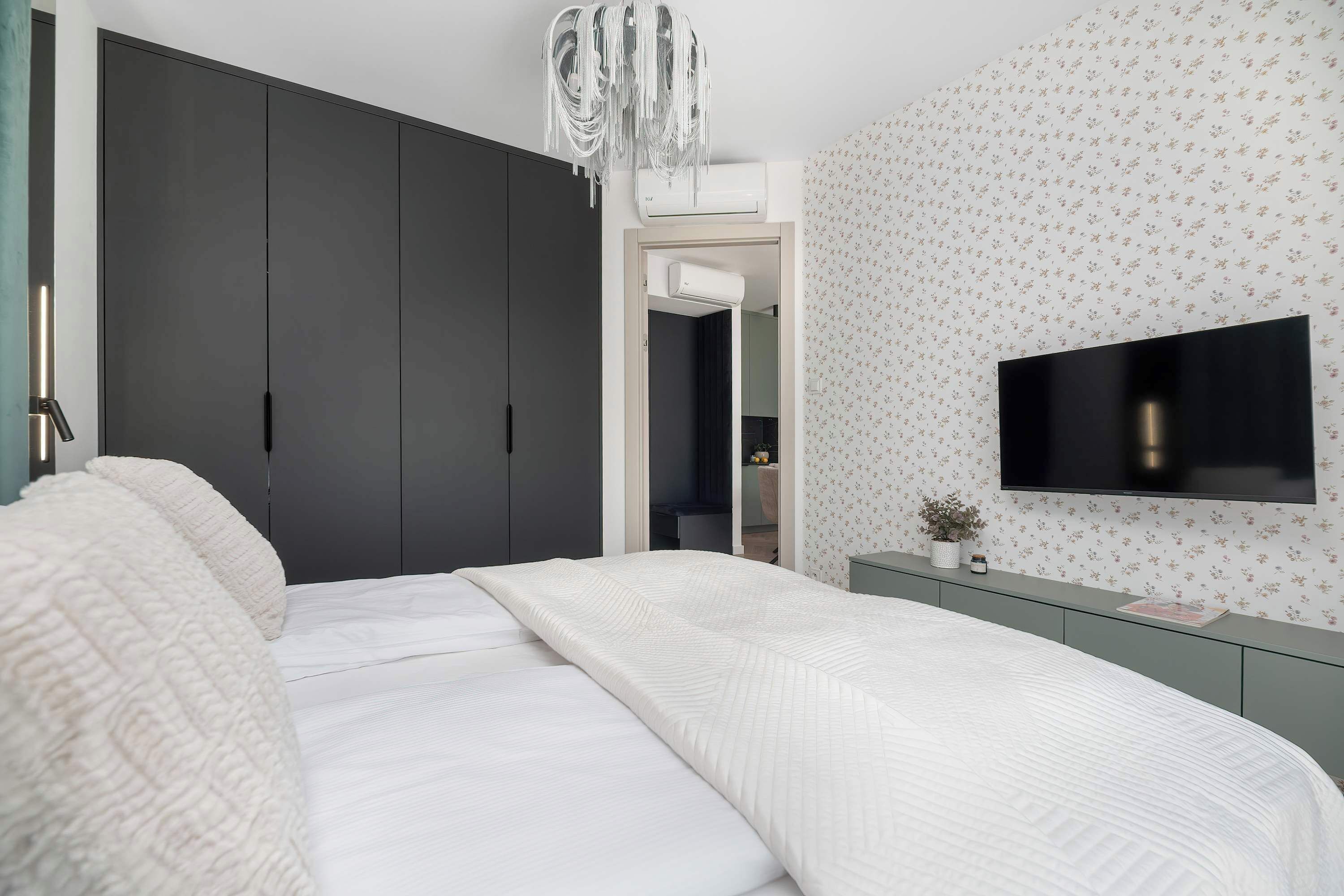 Ein modernes Schlafzimmer mit Bett, Fernseher und Kleiderschrank.