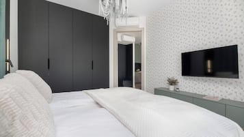 Ein modernes Schlafzimmer mit Bett, Fernseher und Kleiderschrank.