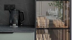 A modern kitchen with a black marble countertop, a coffee maker, and a glass display cabinet with glassware. - Stylish Apartments with Balconies | Panoramic Terrace | Close to the Brine Graduation Towers (Ciechocinek)