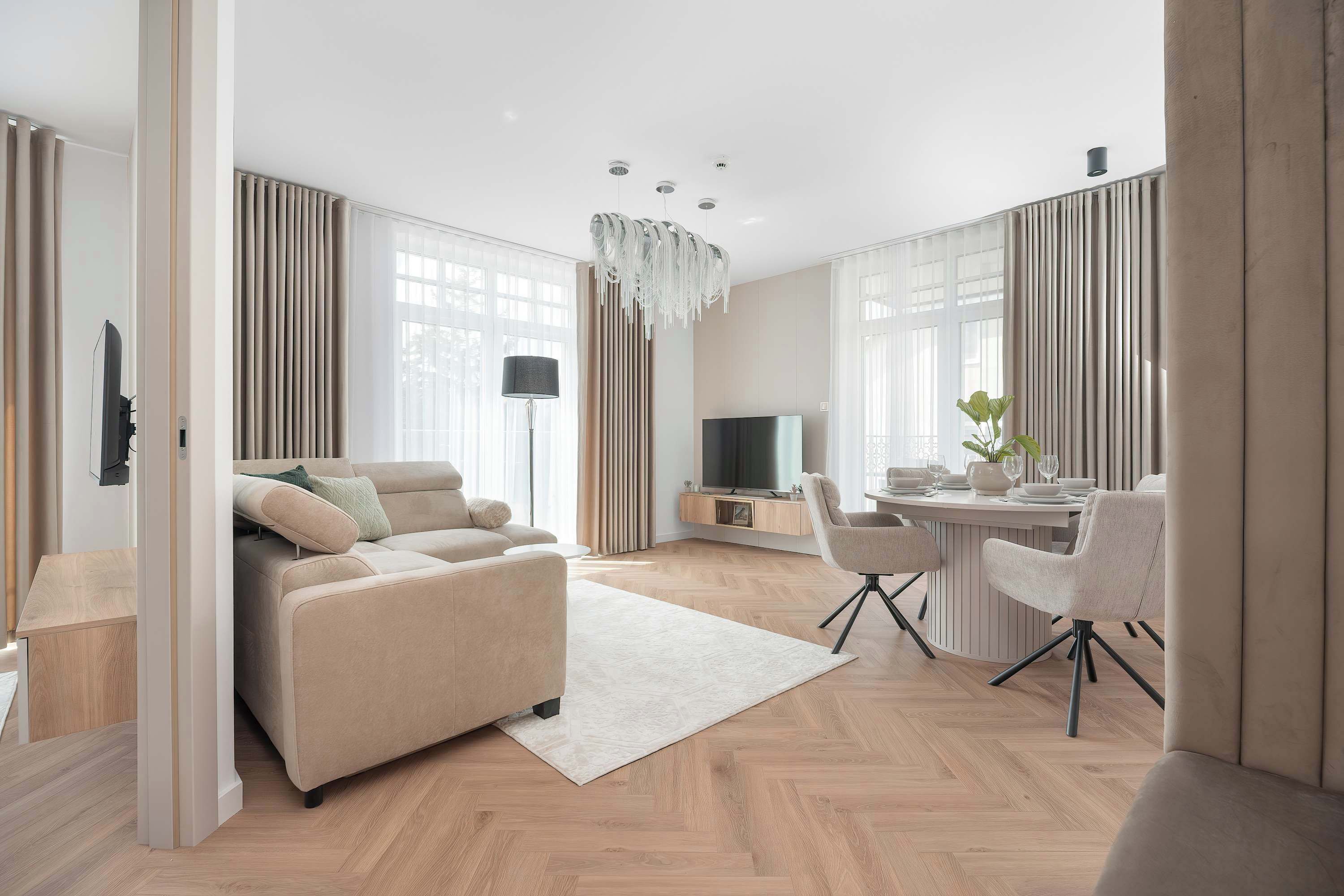 Ein modernes Wohnzimmer mit Sofa, Fernseher, Esstisch und Stühlen.