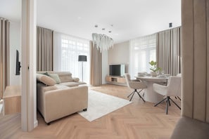 Una sala de estar moderna con un sofá, televisión, mesa de comedor y sillas.