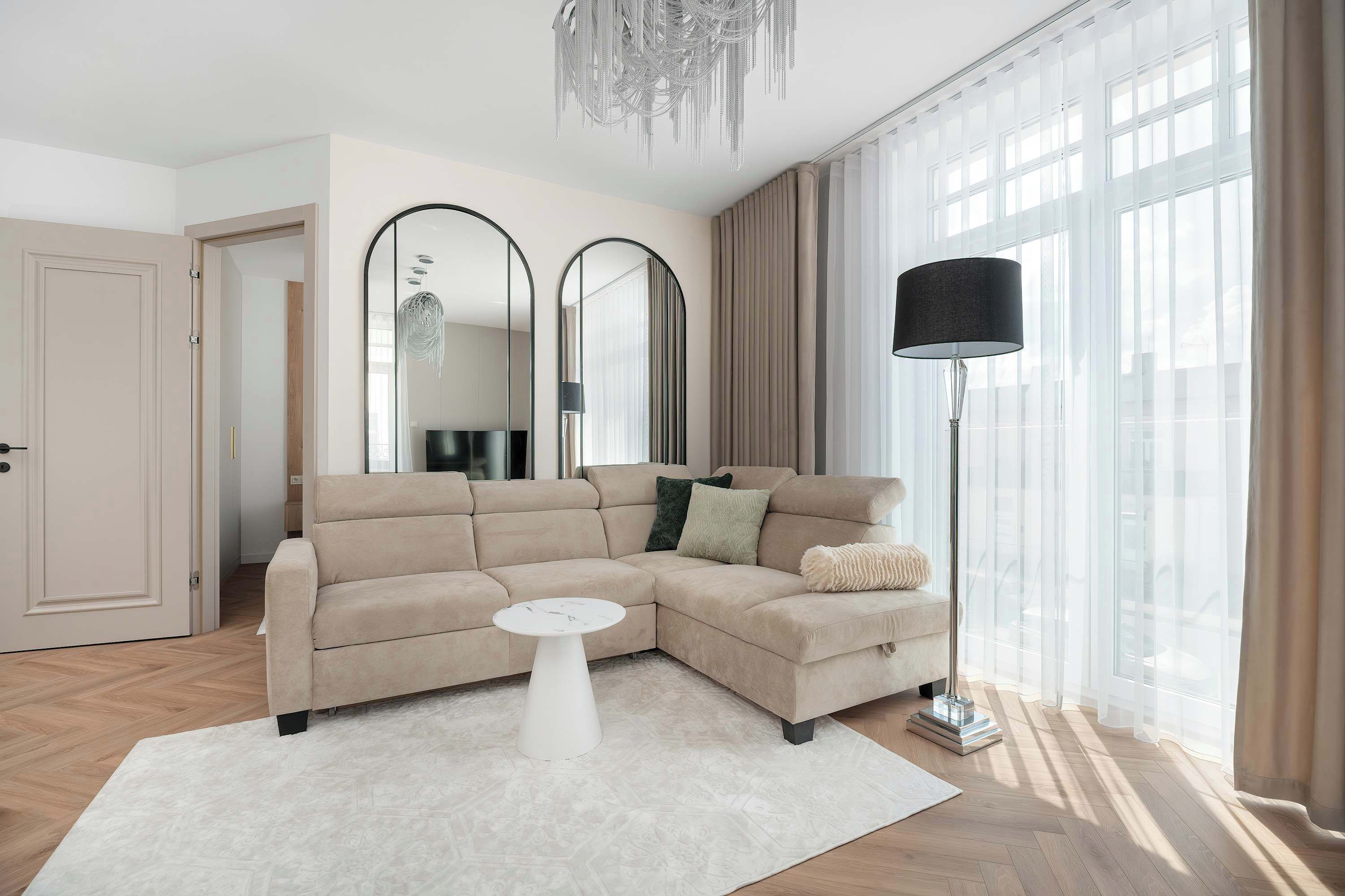 Een moderne woonkamer met een beige modulaire bank, een witte salontafel en een vloerlamp.