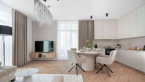 A modern kitchen with a dining area, a flat-screen TV, and a chandelier. - Stylish Apartments with Balconies | Panoramic Terrace | Close to the Brine Graduation Towers (Ciechocinek)