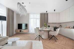 A modern kitchen with a dining area, a flat-screen TV, and a chandelier. - Stylish Apartments with Balconies | Panoramic Terrace | Close to the Brine Graduation Towers (Ciechocinek)