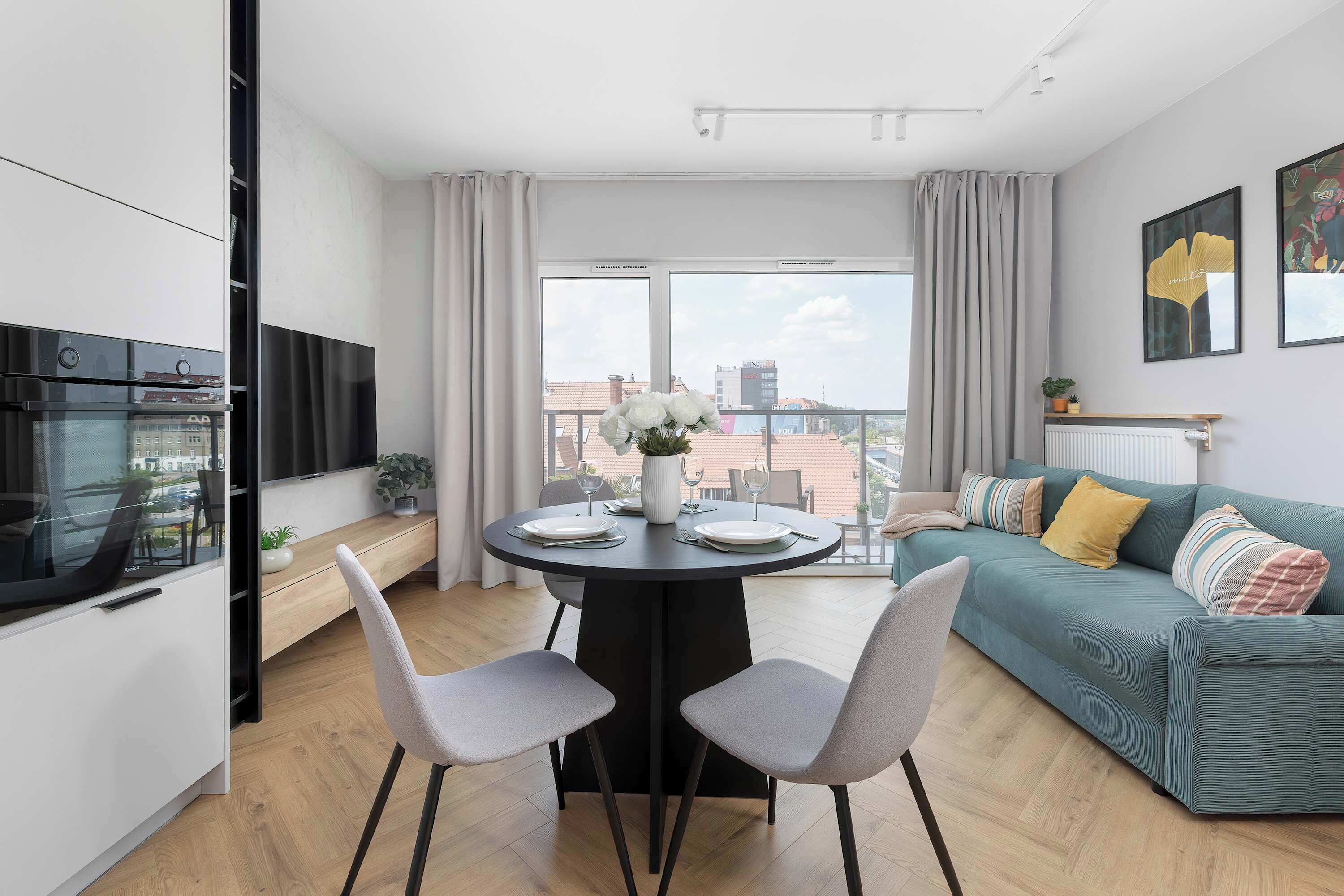 A modern apartment with a dining area, a sofa, and a kitchen.