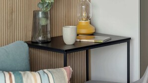 Un espace de vie moderne comprenant un canapé, une petite table, une lampe et une plante décorative.