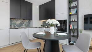 Une cuisine moderne avec des meubles de couleur sombre, un pare-feu en marbre et un coin repas comprenant une table ronde et deux chaises.