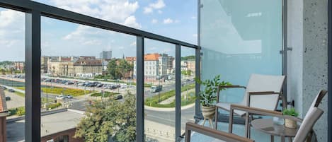 Un balcón con vista a un paisaje urbano, que incluye edificios y una carretera.