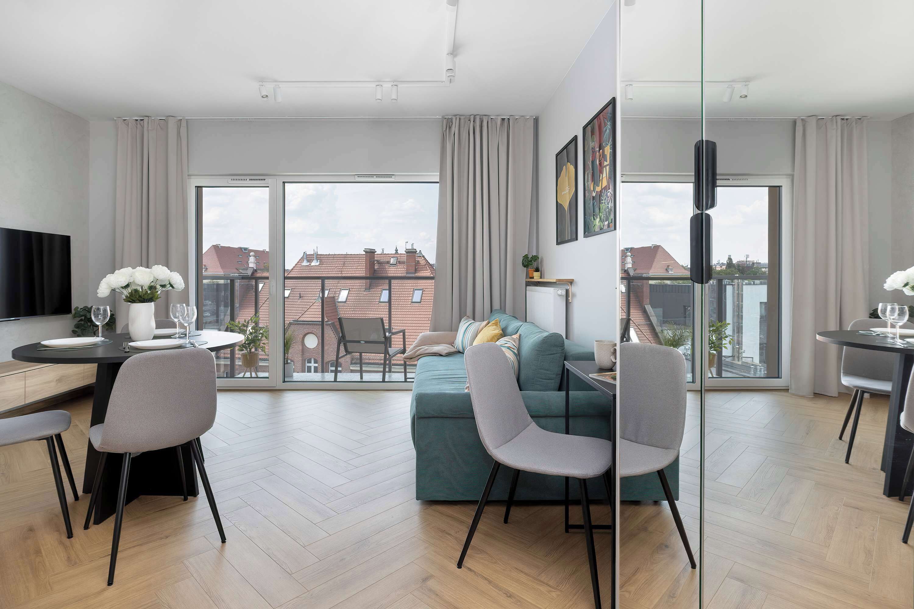 A modern apartment with a dining area, a sofa, and a TV.