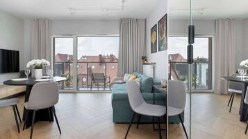 A modern apartment with a dining area, a sofa, and a TV.