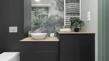 A modern bathroom with a large mirror, a white basin, and a black cabinet.