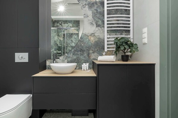 A modern bathroom with a large mirror, a white basin, and a black cabinet.