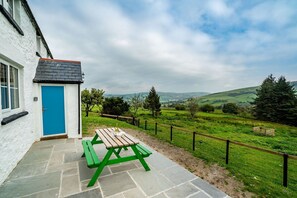 Ein Haus mit blauer Tür und einem Picknicktisch draußen.
