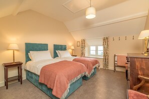 Ein Schlafzimmer mit zwei Betten, einem Schreibtisch und einem Fenster mit Vorhängen.