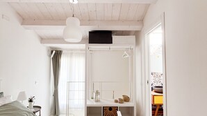Ein Schlafzimmer mit Bett, Nachttischen, einem Kleiderschrank und Blick ins Freie.