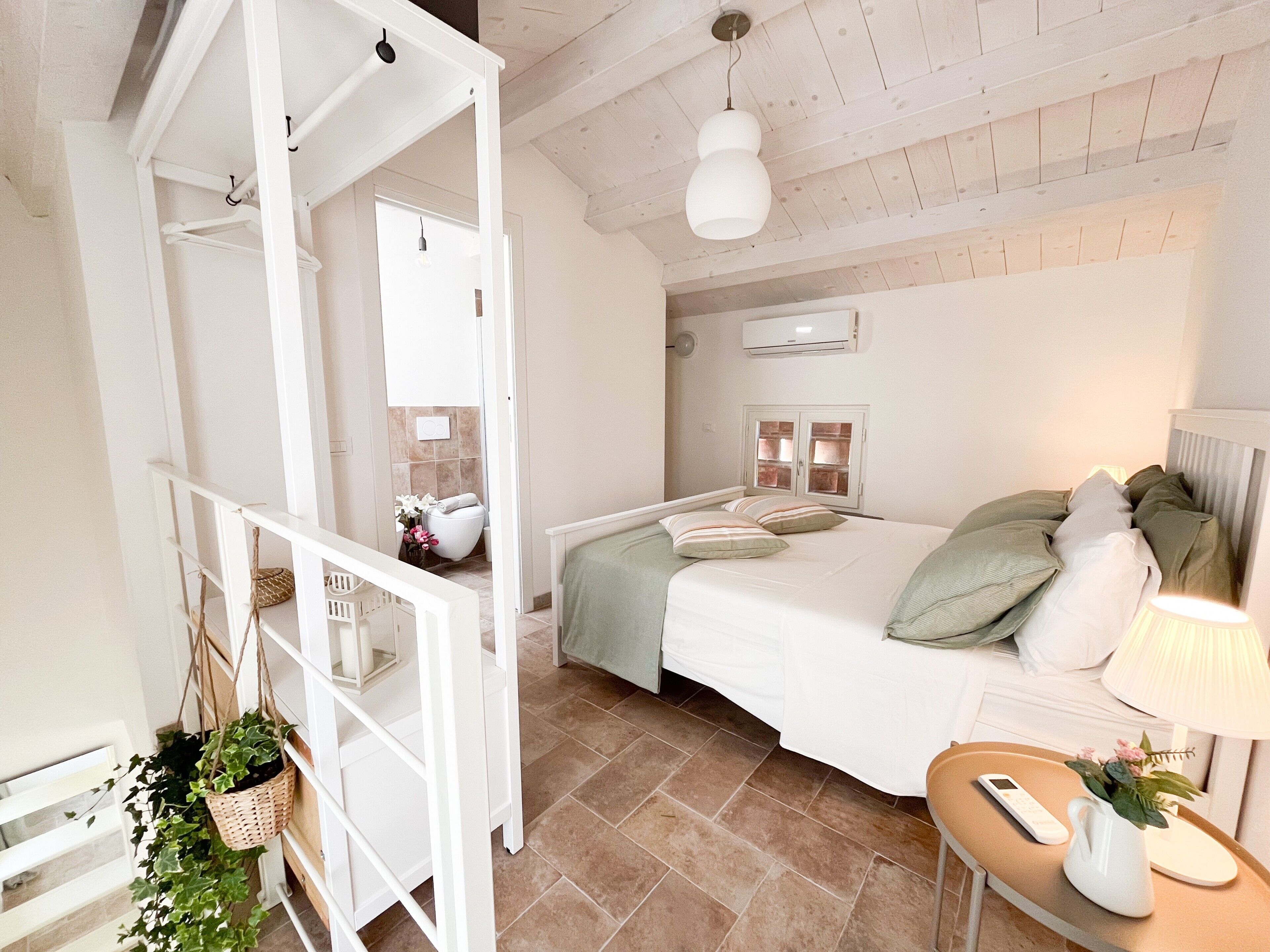Une chambre à coucher avec un lit, une table de chevet, une lampe et une plante suspendue.