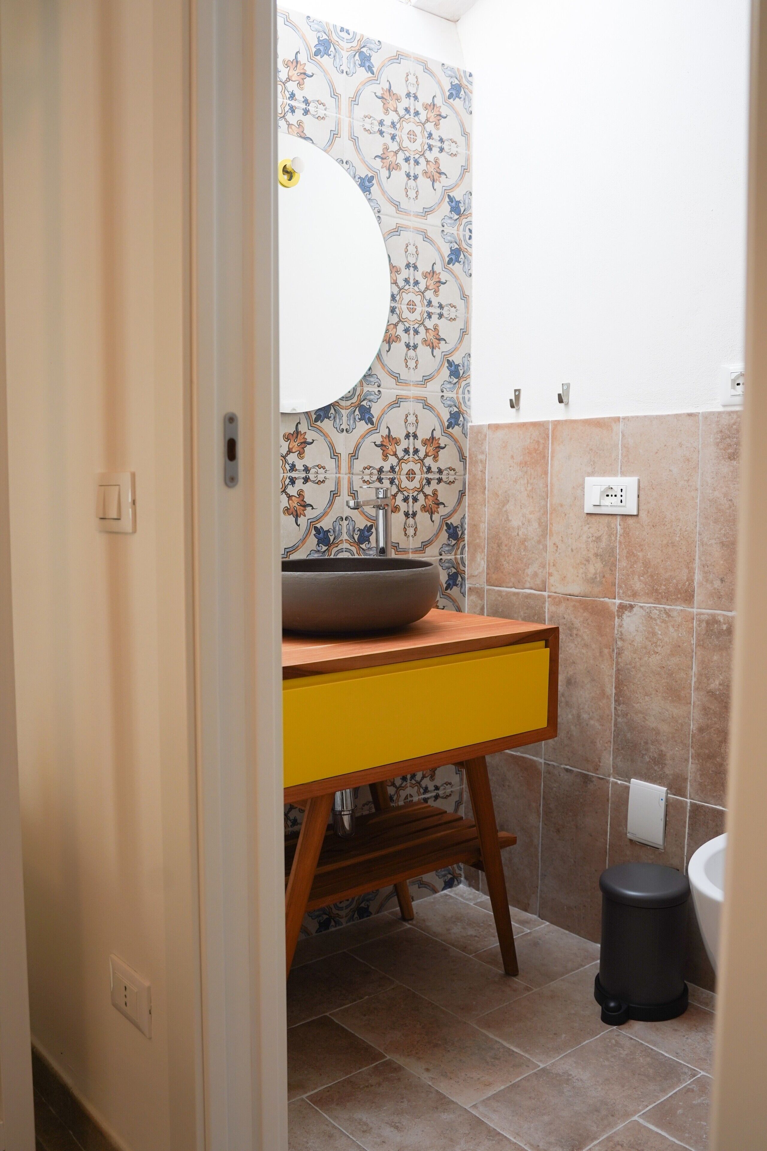 A bathroom with a wooden vanity, a bowl sink, and a toilet.