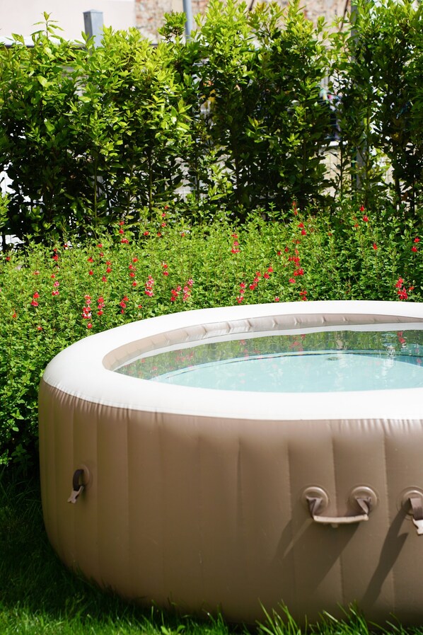 Un jacuzzi rodeado de vegetación exuberante y flores rojas.
