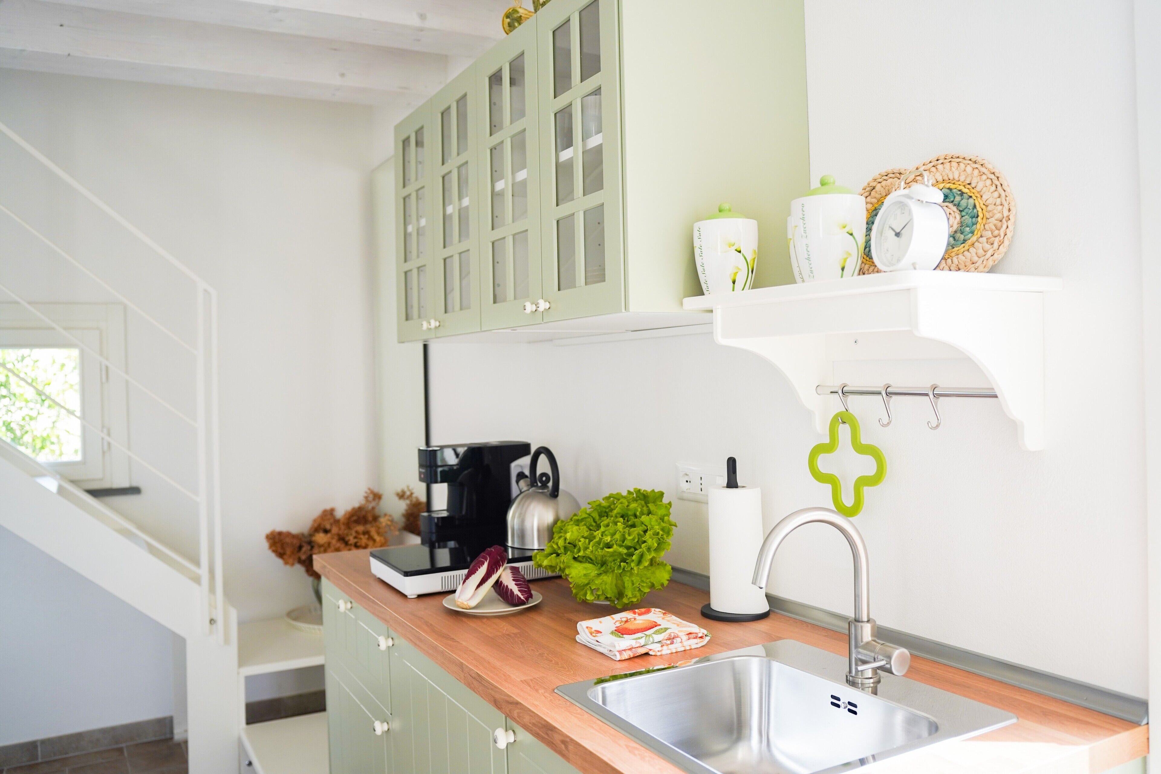 A modern kitchen with a wooden countertop, stainless steel sink, and a coffee maker.