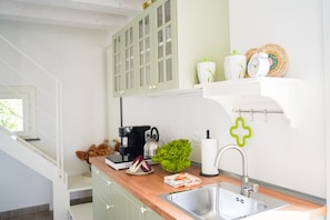 A modern kitchen with a wooden countertop, stainless steel sink, and a coffee maker.