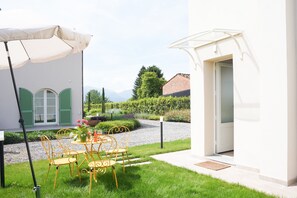 Un cortile con tavolo e sedie, una zona relax coperta e l'ingresso di un edificio.
