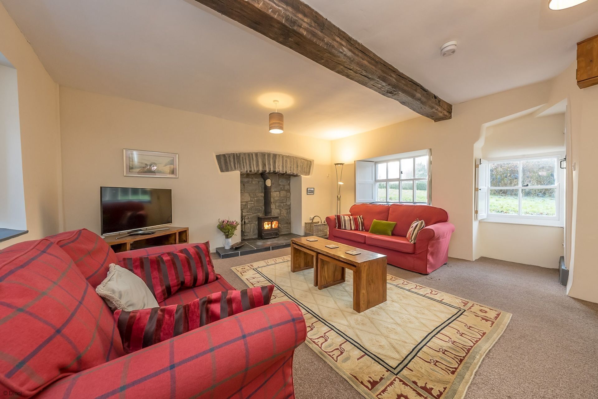 A living room with a fireplace, a television, a red sofa, and a coffee table.