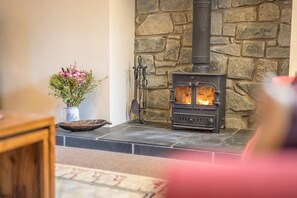 A stone wall with a wood-burning stove in a room. - Cosy Cottage Near Beach with Games Room | Bwthyn-Bryn-Hir (Criccieth)