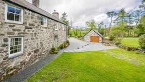 Une maison en pierre avec une allée en gravier menant à une porte en bois.
