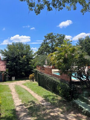 A garden with a swimming pool, a brick wall, and a pathway.