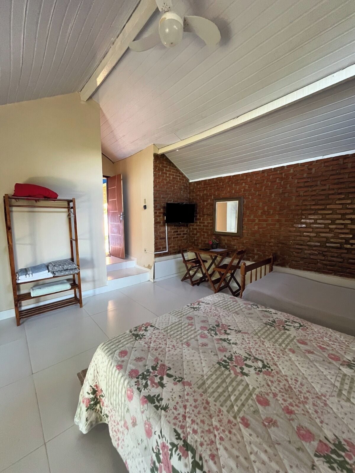 Een slaapkamer met een bed, een bureau, een televisie en een bakstenen muur.