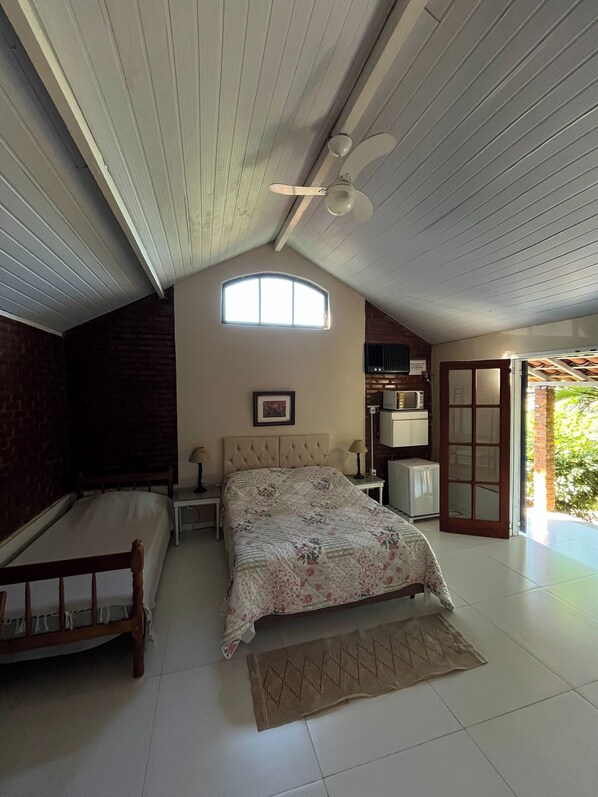 A bedroom with a bed, a nightstand, a ceiling fan, a window, and a door leading to a balcony.