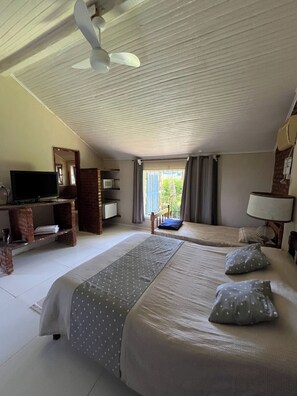 A hotel room with two beds, a television, a desk, and a window with curtains.