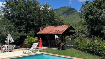 A swimming pool with a tiled edge, surrounded by a grassy area and a brick structure.