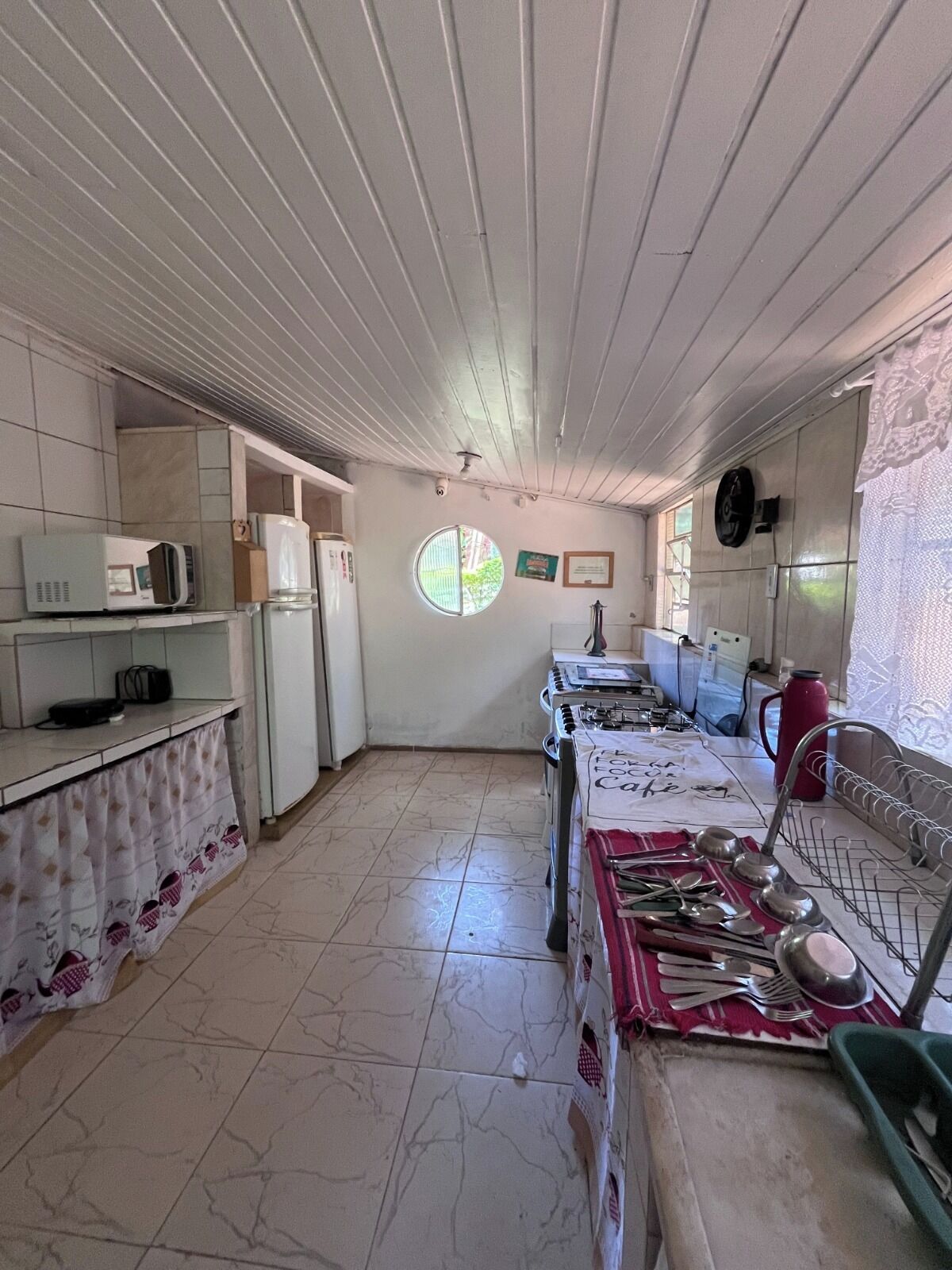 A compact kitchen with a microwave, refrigerator, and a sink with a dish rack.