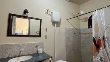 Un baño con inodoro, lavamanos, ducha y espejo.