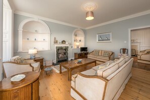 Una sala de estar con chimenea, sofá, mesa de centro y televisor.