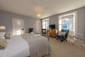 A bedroom with a bed, a dresser, a television, and a chair. - Georgian Country House and Stable Sleeping 18 | Gorwel-Bryn-Hir (Criccieth)
