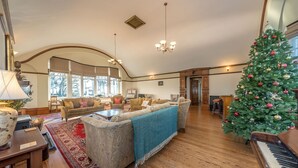 A spacious living room with a grand staircase, a piano, and a decorated Christmas tree. - Georgian Country House and Stable Sleeping 18 | Gorwel-Bryn-Hir (Criccieth)