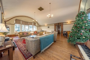 A spacious living room with a grand staircase, a piano, and a decorated Christmas tree. - Georgian Country House and Stable Sleeping 18 | Gorwel-Bryn-Hir (Criccieth)