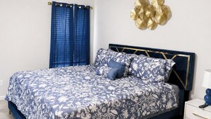 A bedroom with a bed, a nightstand, a wall-mounted decorative item, and a ceiling fan. - Spacious 4-bedroom house in enjoyable Stonecrest with AC (Stonecrest)