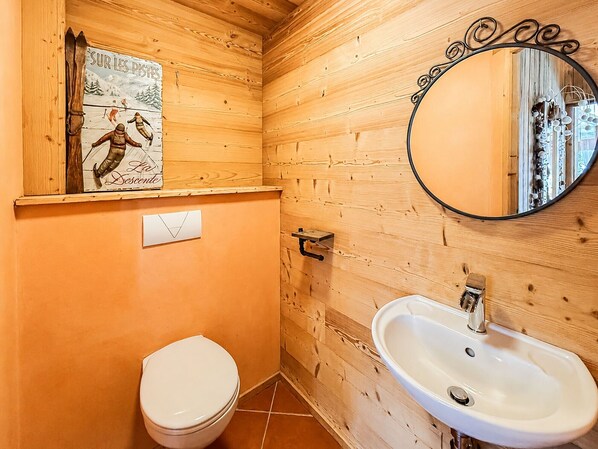 Ein Badezimmer im Holzstil mit Toilette, Waschbecken und Spiegel.