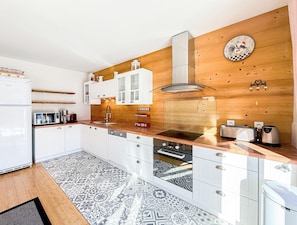 Eine moderne Küche mit weißen Schränken, einer Holzrückwand und einer Uhr.