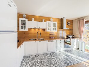 Eine moderne Küche mit Holzvertäfelung, weißen Schränken, einer Spüle und einem Einbauofen.